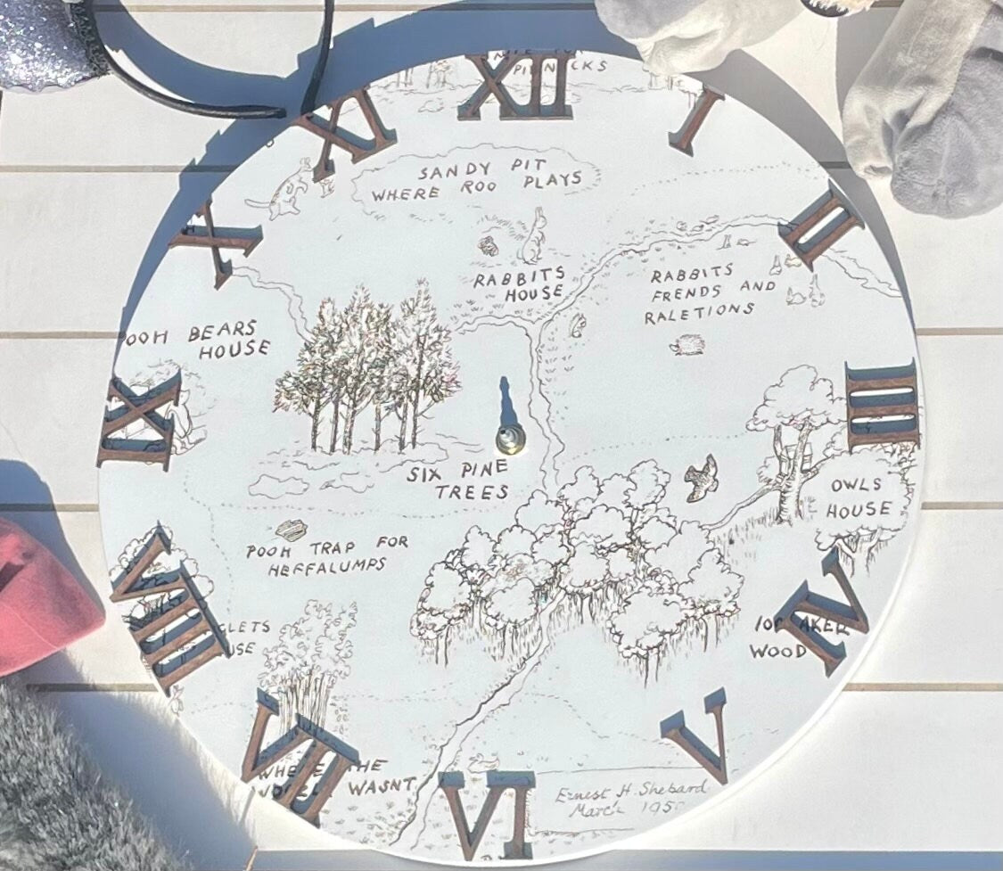 Decorative clock with a map design and Roman numerals on a wooden surface.