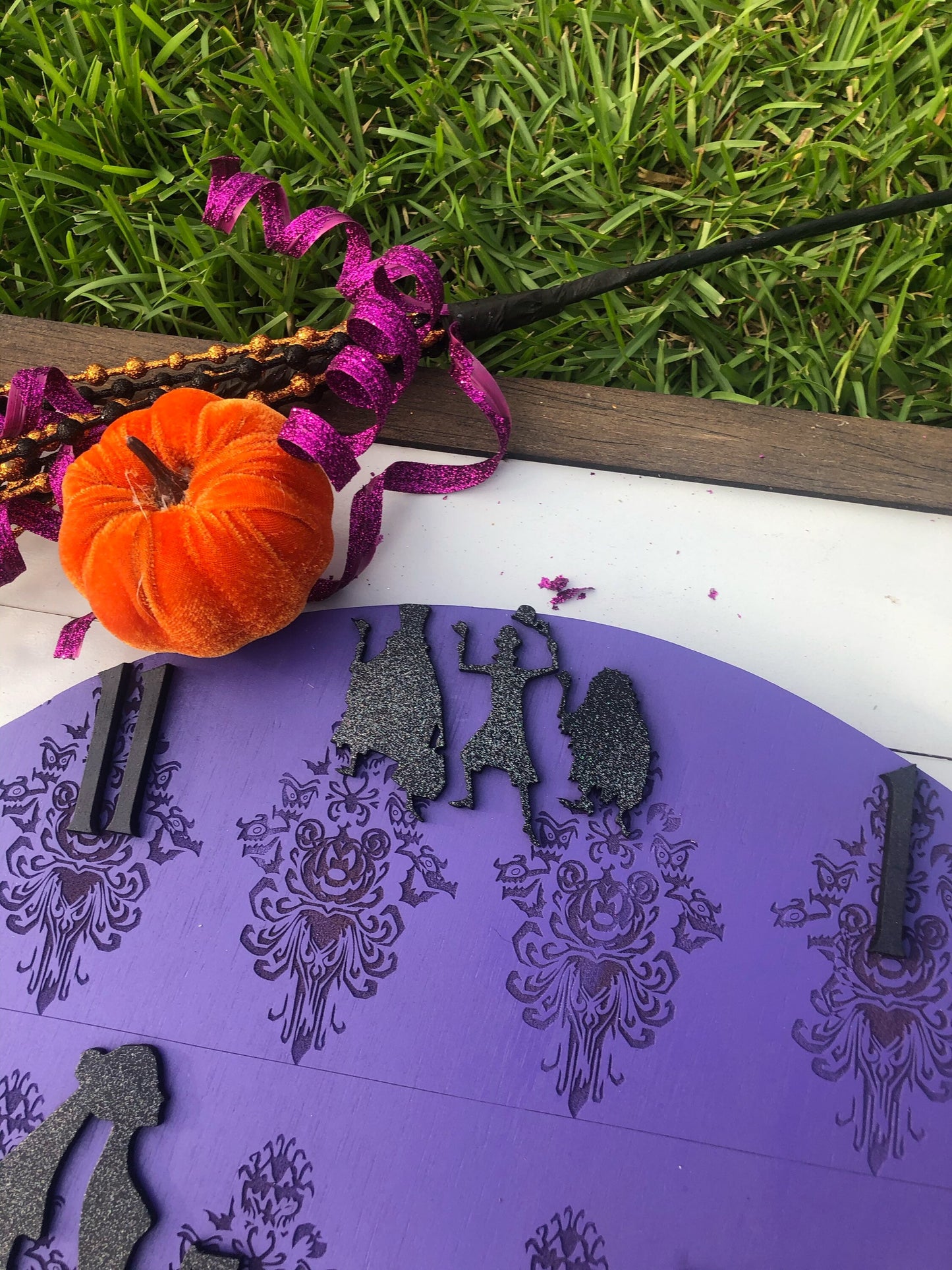 Purple decorative item with black cut-out figures on grass