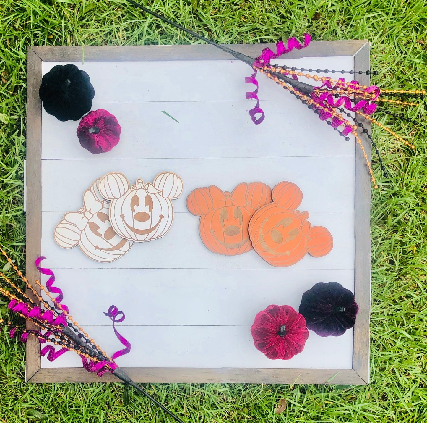 Decorative wooden signs with pumpkin and ghost designs on a grass background