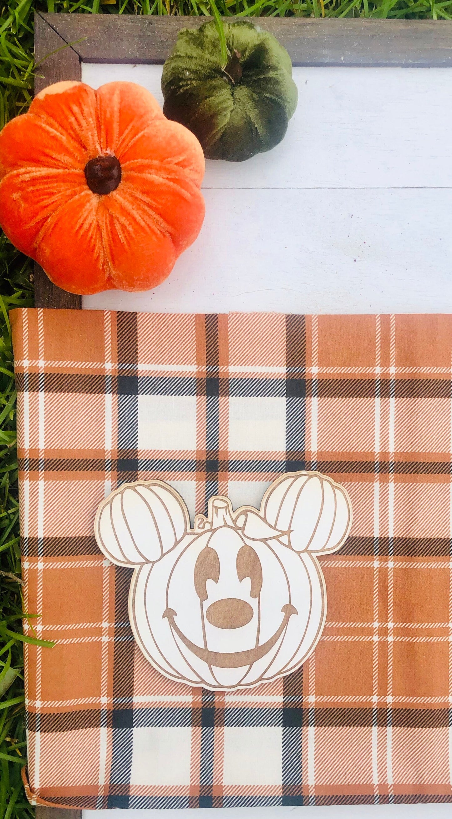 Plaid blanket with Mickey Mouse pumpkin design, orange and green pumpkins on a white surface.