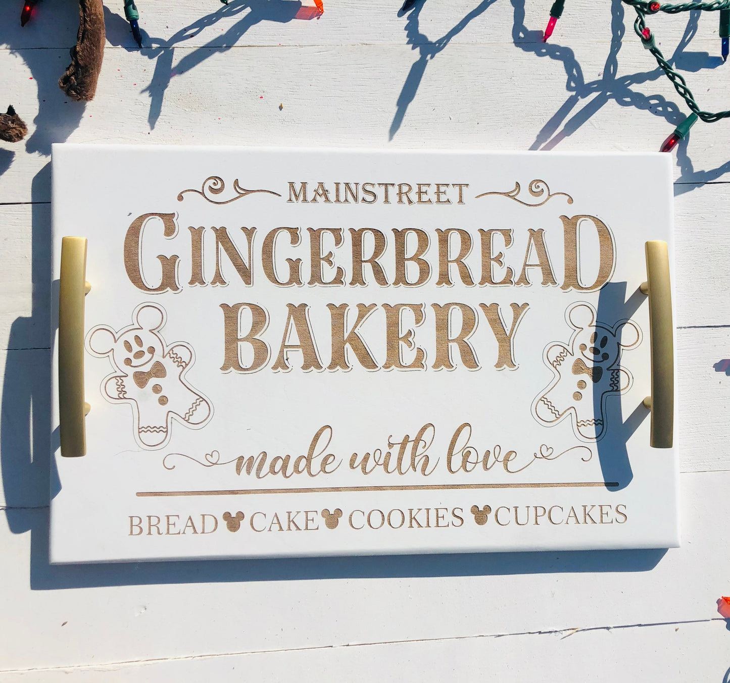 Wooden tray with 'Mainstreet Gingerbread Bakery' text and gingerbread men graphics on a wooden surface.