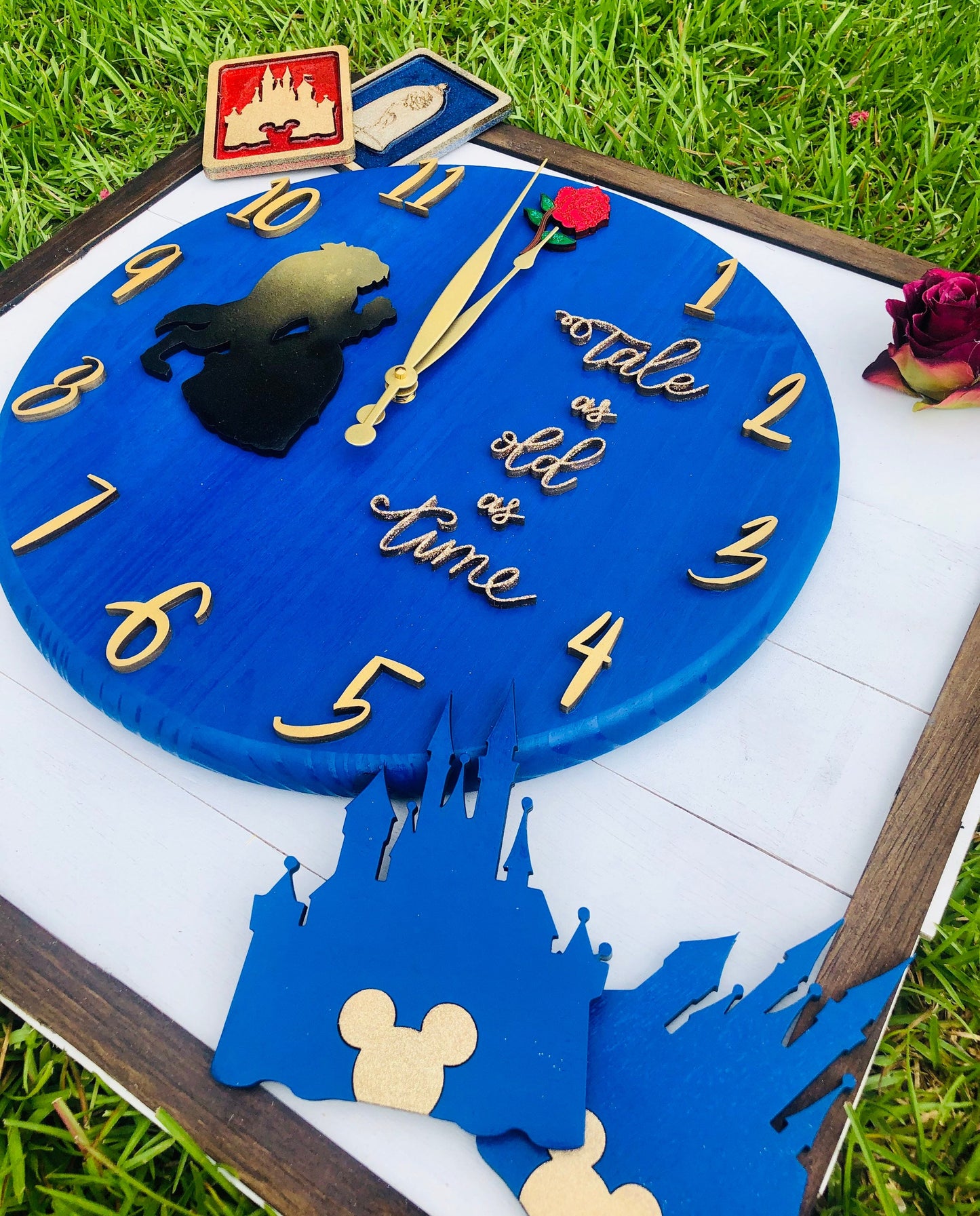 Decorative clock with castle and rose design on a grassy background