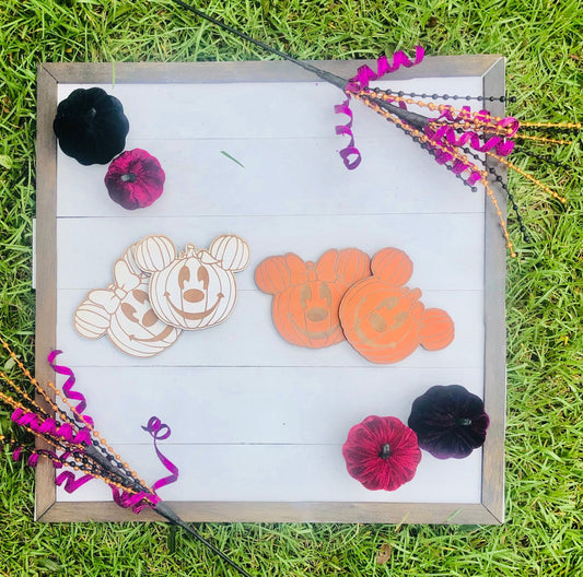 Decorative wooden signs with pumpkin and ghost designs on a grass background