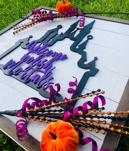 Decorative Halloween sign with purple and black text on a white background, surrounded by Halloween decorations.