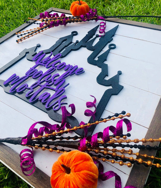 Decorative Halloween sign with purple and black text on a white background, surrounded by Halloween decorations.