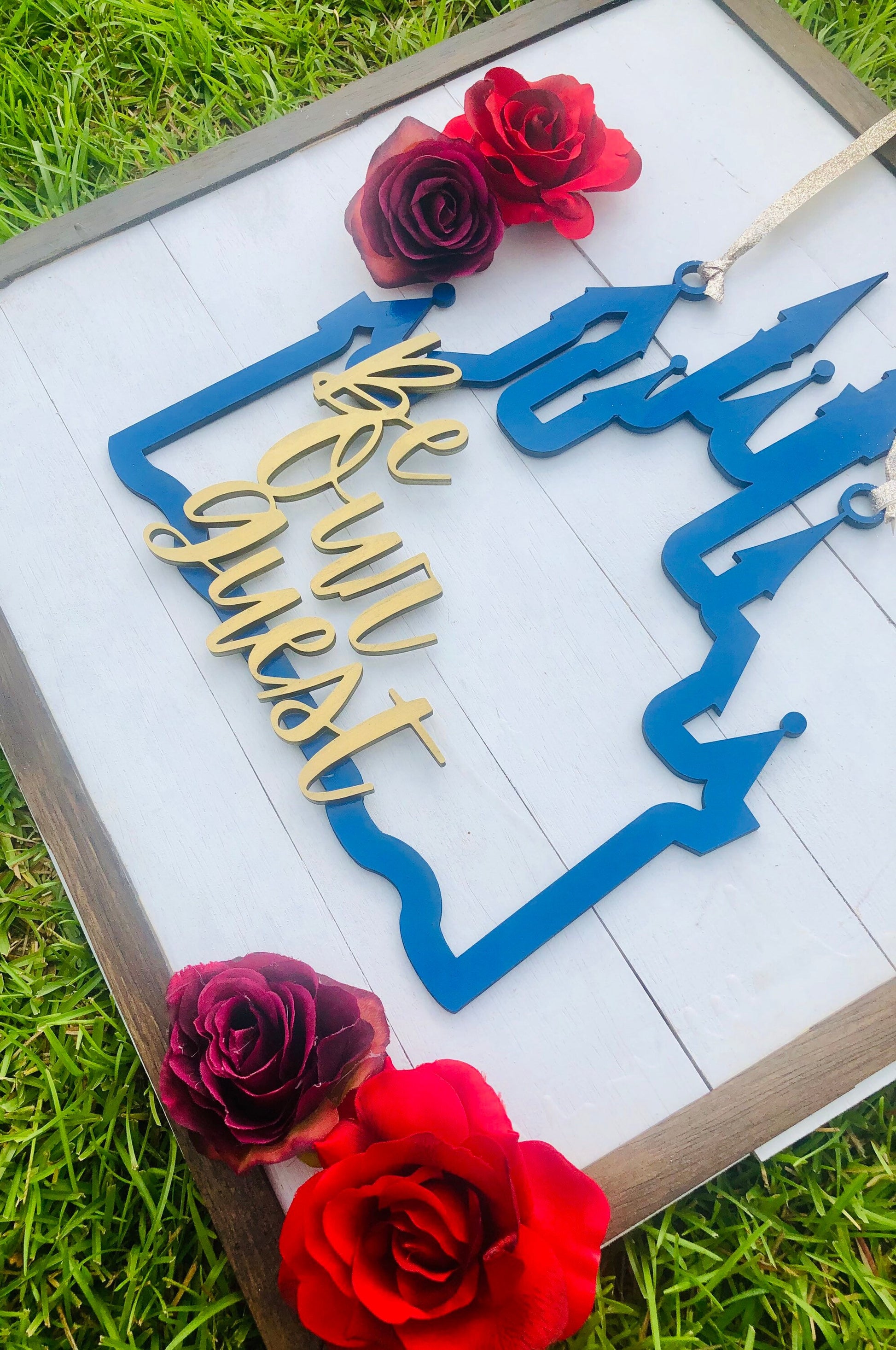 Decorative sign with 'We will wait' text on a white background with red roses.
