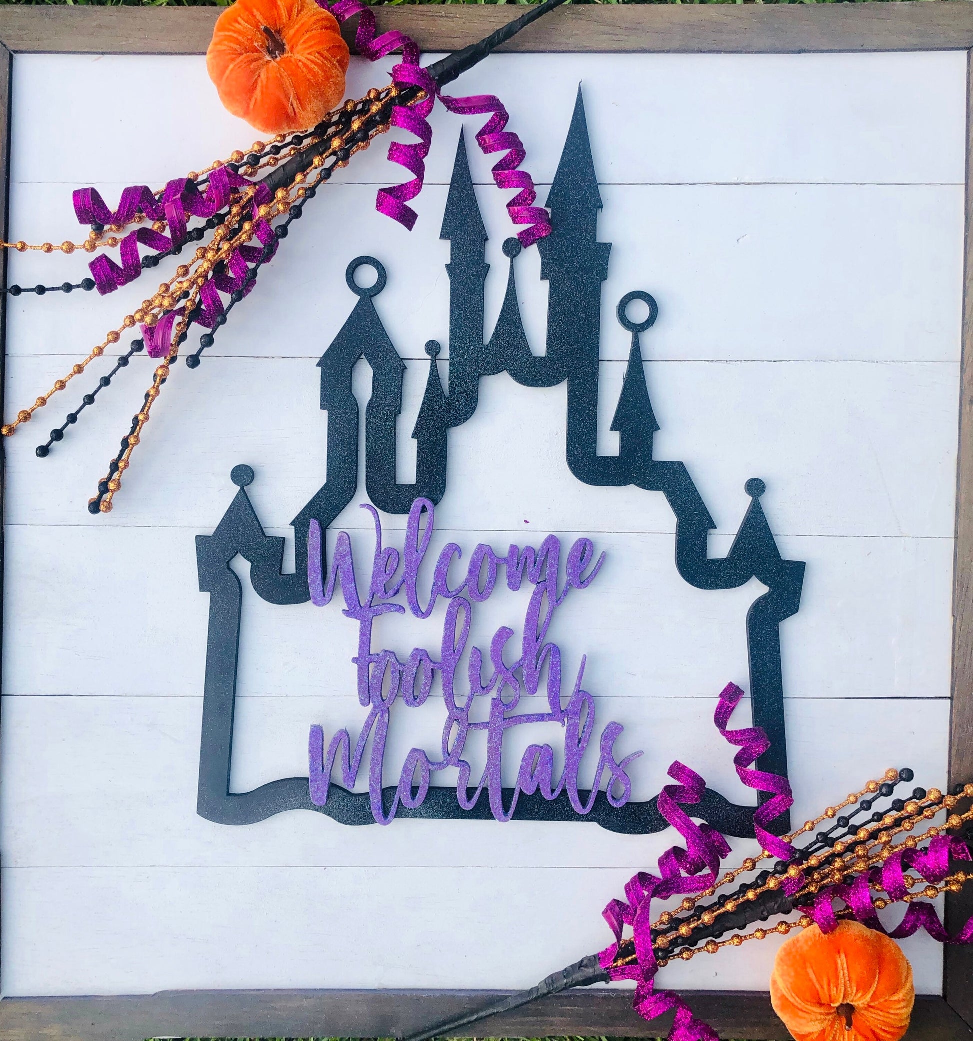 Halloween-themed decorative sign with castle design and 'Welcome Foolish Mortals' text on a white background.