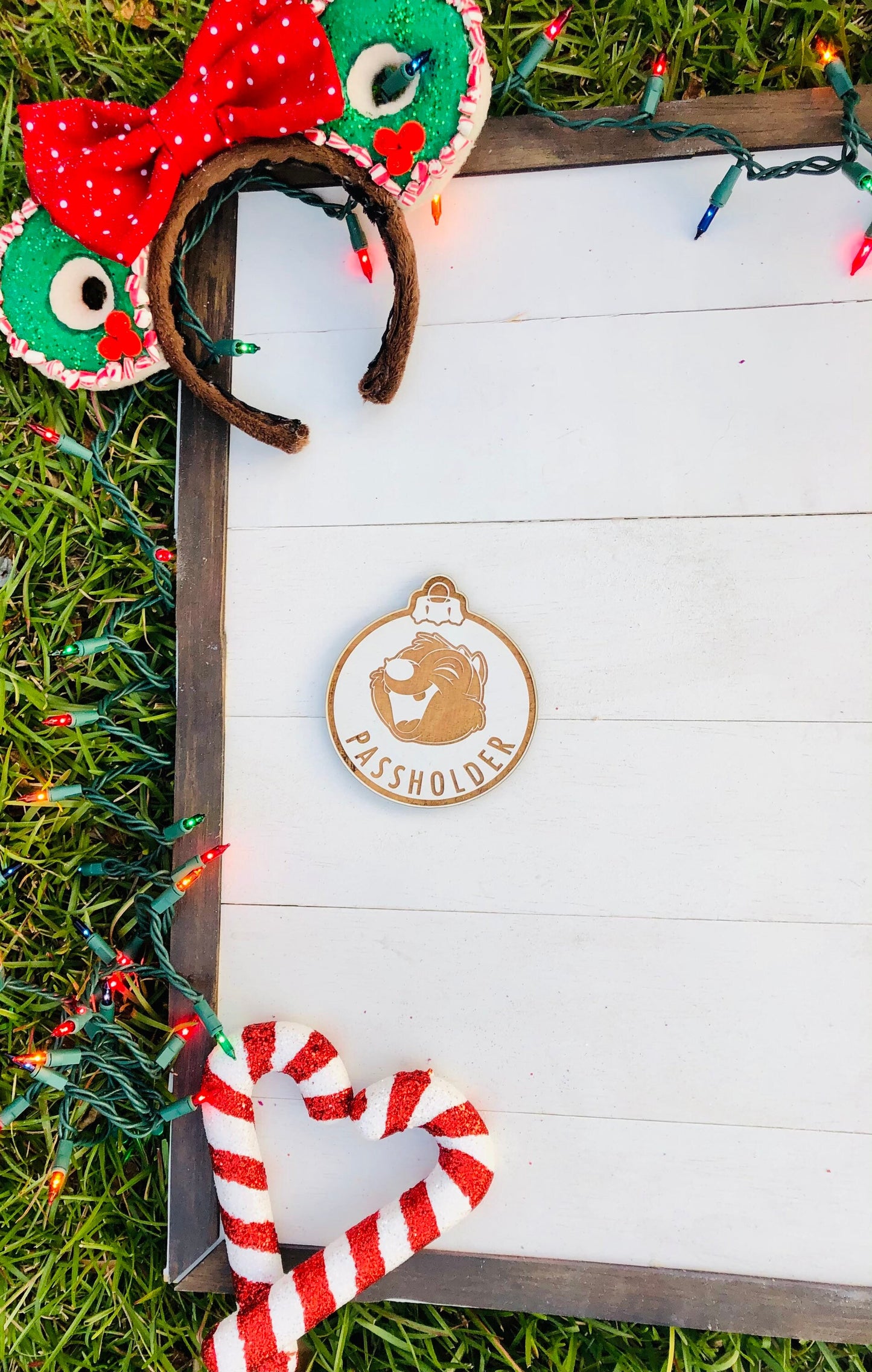 Decorative headband with red and green polka dot bow, candy cane design, and wooden ornament on a white surface.