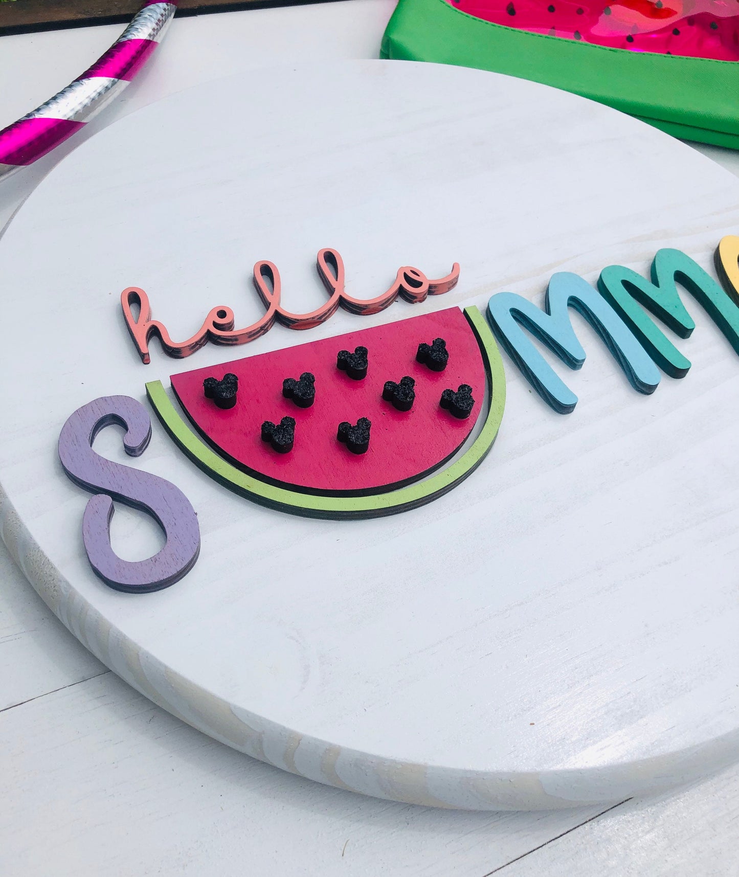 Decorative sign with watermelon design and 'hello summer' text on a white surface.