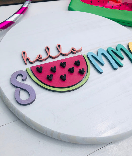 Decorative sign with watermelon design and 'hello summer' text on a white surface.