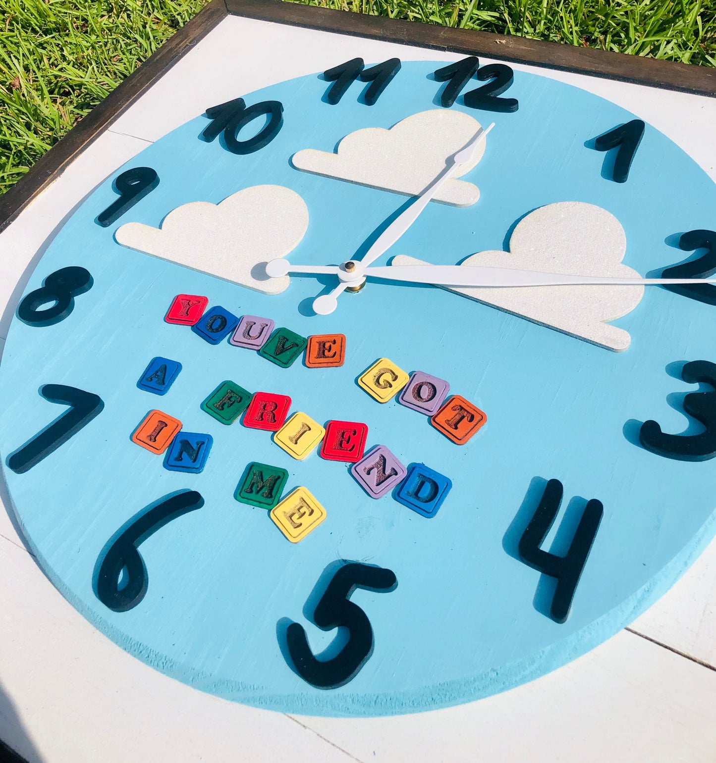 Children's clock with colorful letters spelling out a message on a blue background