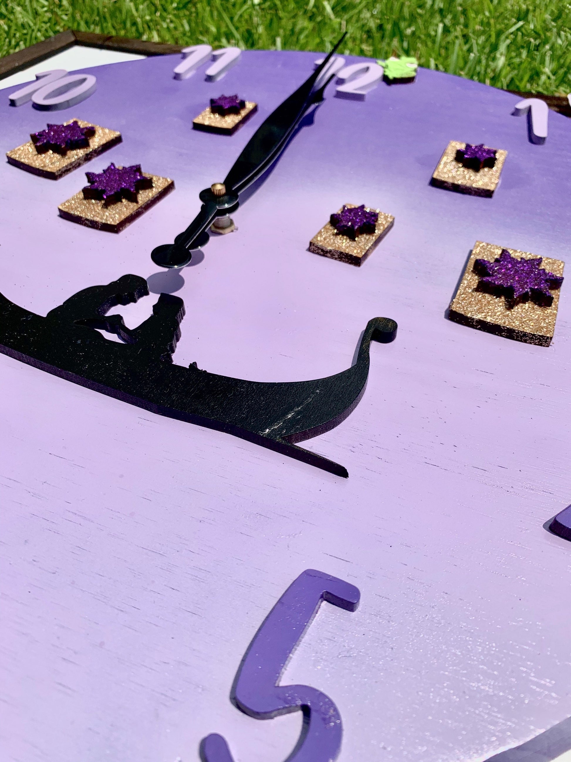 Decorative clock with purple accents and black hands on a white surface.