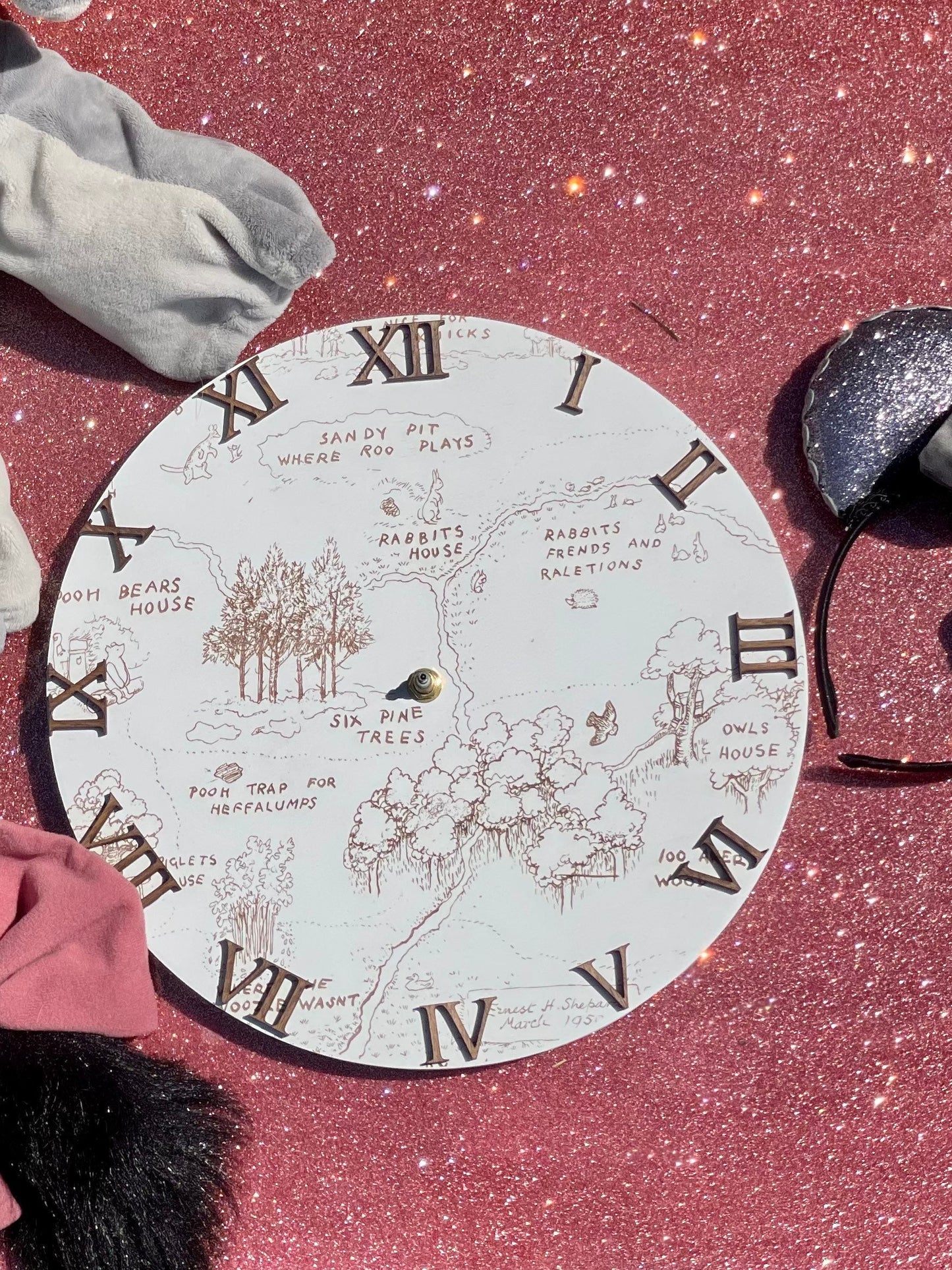 Round decorative board with Roman numeral design on a pink glittery surface