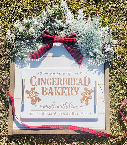 Decorative sign for Mainstreet Gingerbread Bakery with gingerbread men graphics on a grass background.
