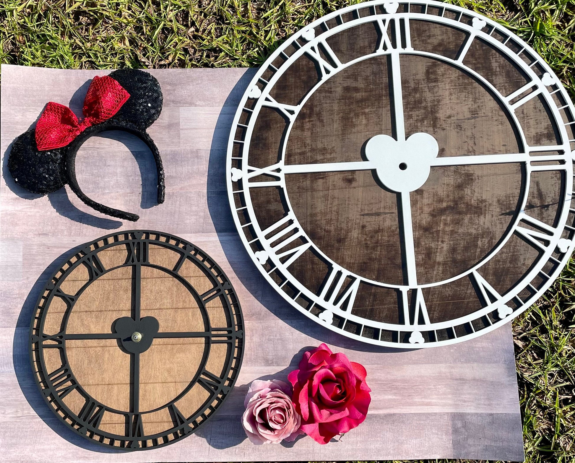 Decorative clock faces on a wooden surface with a Minnie Mouse headband and pink rose.
