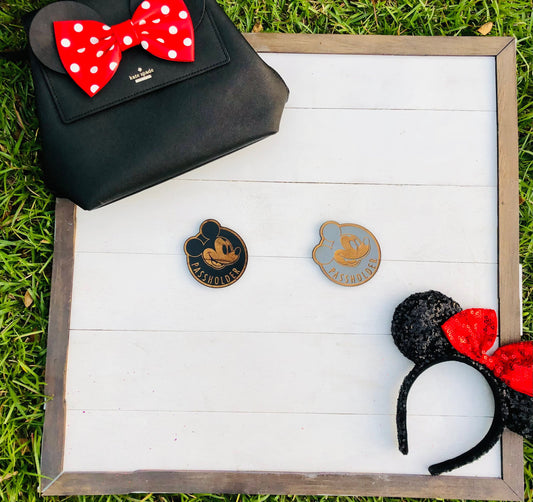 Black handbag with red polka dot bow, two pins on a white wooden board, and black headband with red bow on grass.