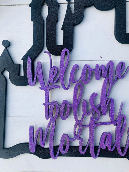 Decorative sign with purple text 'Welcome to the Mortal' on a white background