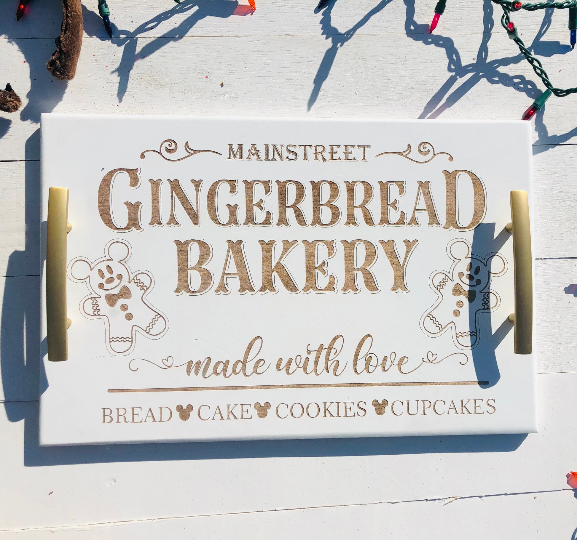 Wooden tray with 'Mainstreet Gingerbread Bakery' text and gingerbread men graphics on a wooden surface.