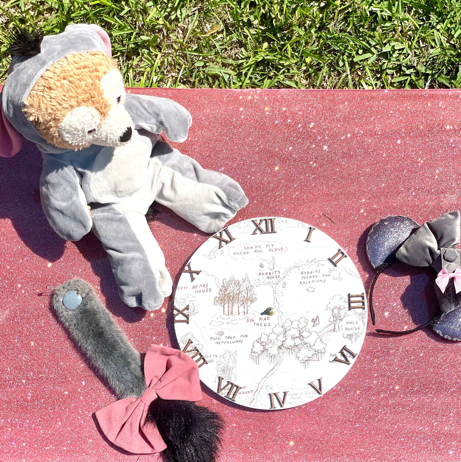 Gray plush toy elephant with a pink bow on a red surface with a circular map design.