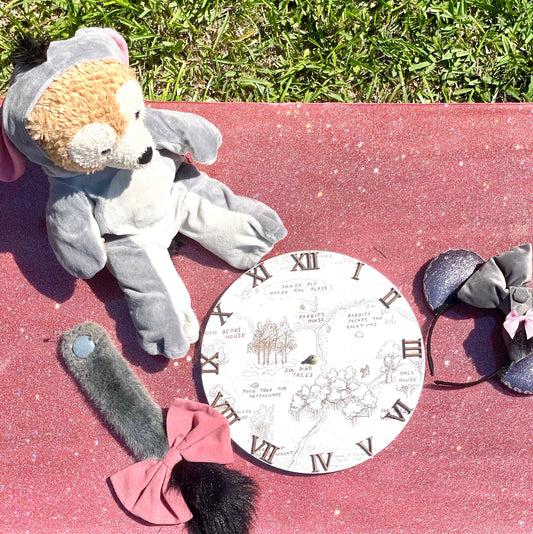 Gray plush toy elephant with a pink bow on a red surface with a circular map design.