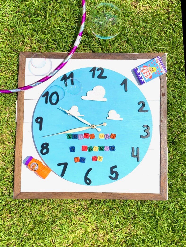 Children's clock with colorful numbers and letters on a grass background