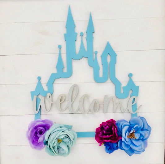 Decorative sign with blue castle design and colorful flowers on a light wooden background