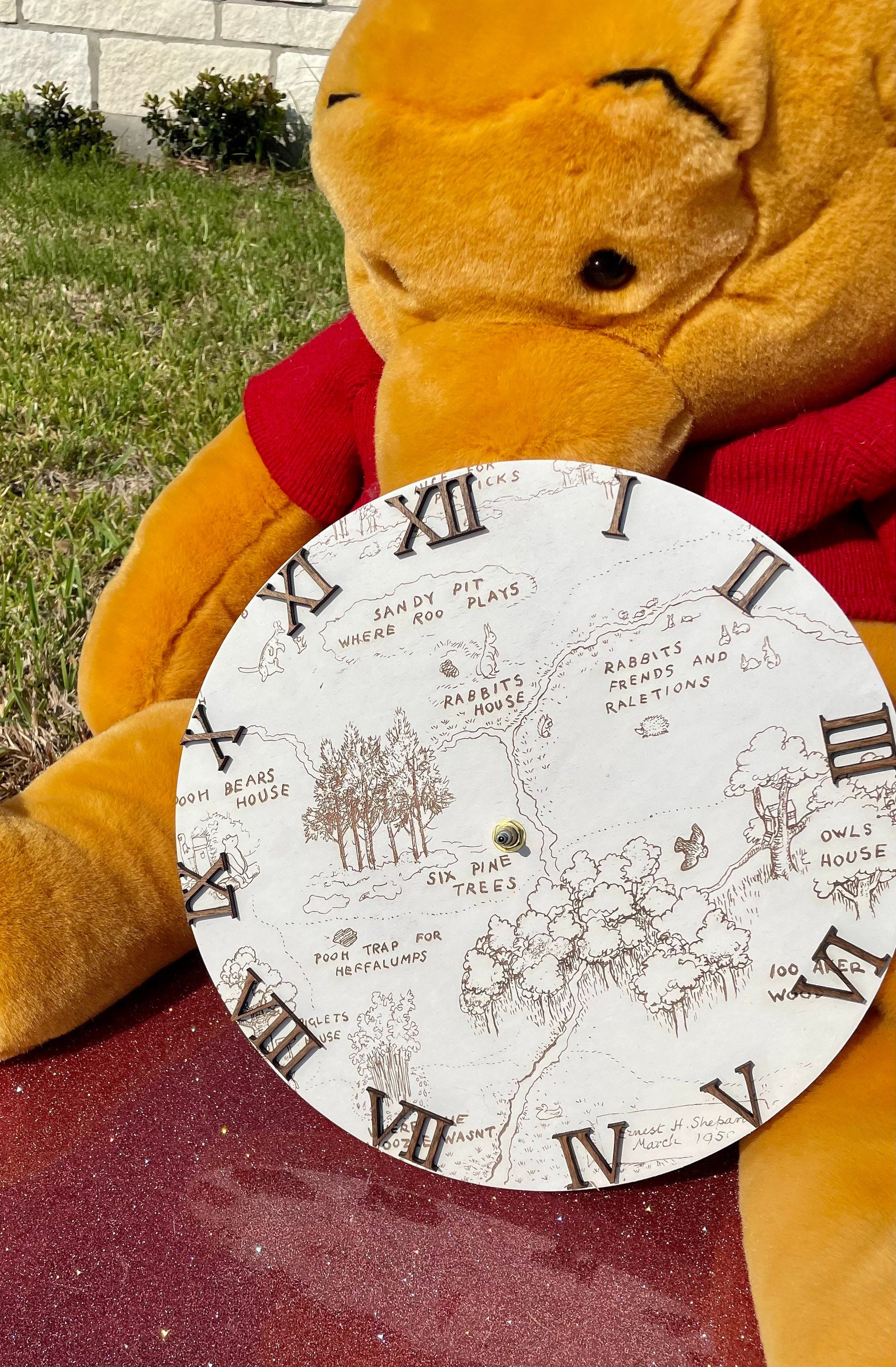 Plush bear holding a map with Roman numeral design on a red surface.