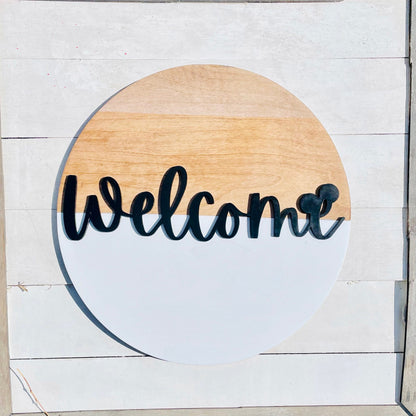 Round wooden sign with 'Welcome' text on a white wooden background