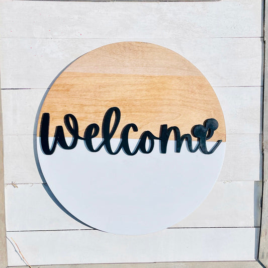 Round wooden sign with 'Welcome' text on a white wooden background