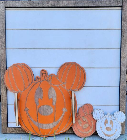 Decorative pumpkin with Mickey Mouse ears on a wooden frame against a light blue background