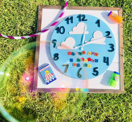Children's clock with colorful numbers and letters on a grassy background