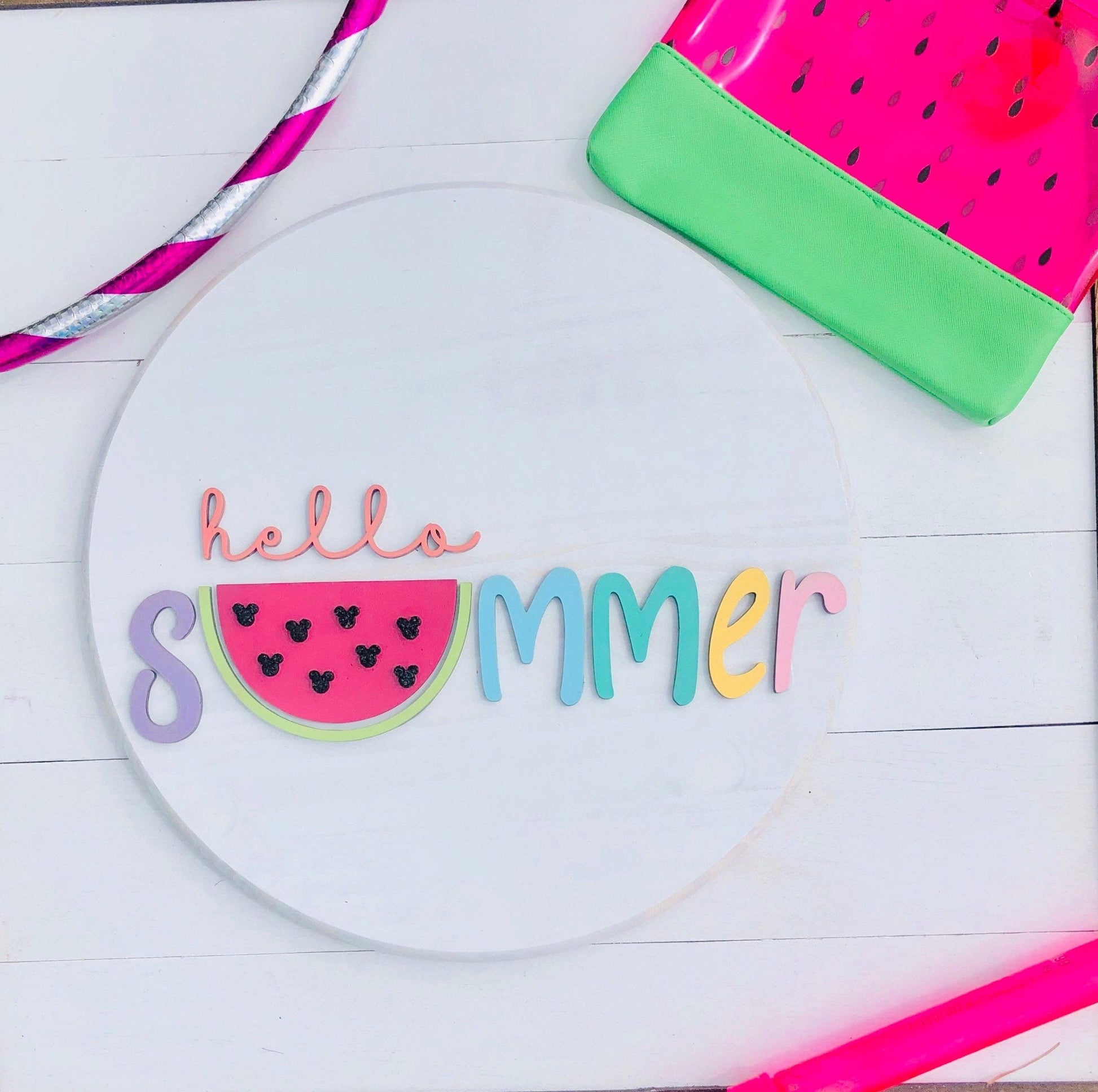 Decorative plate with 'hello summer' text and watermelon design on a white wooden surface.