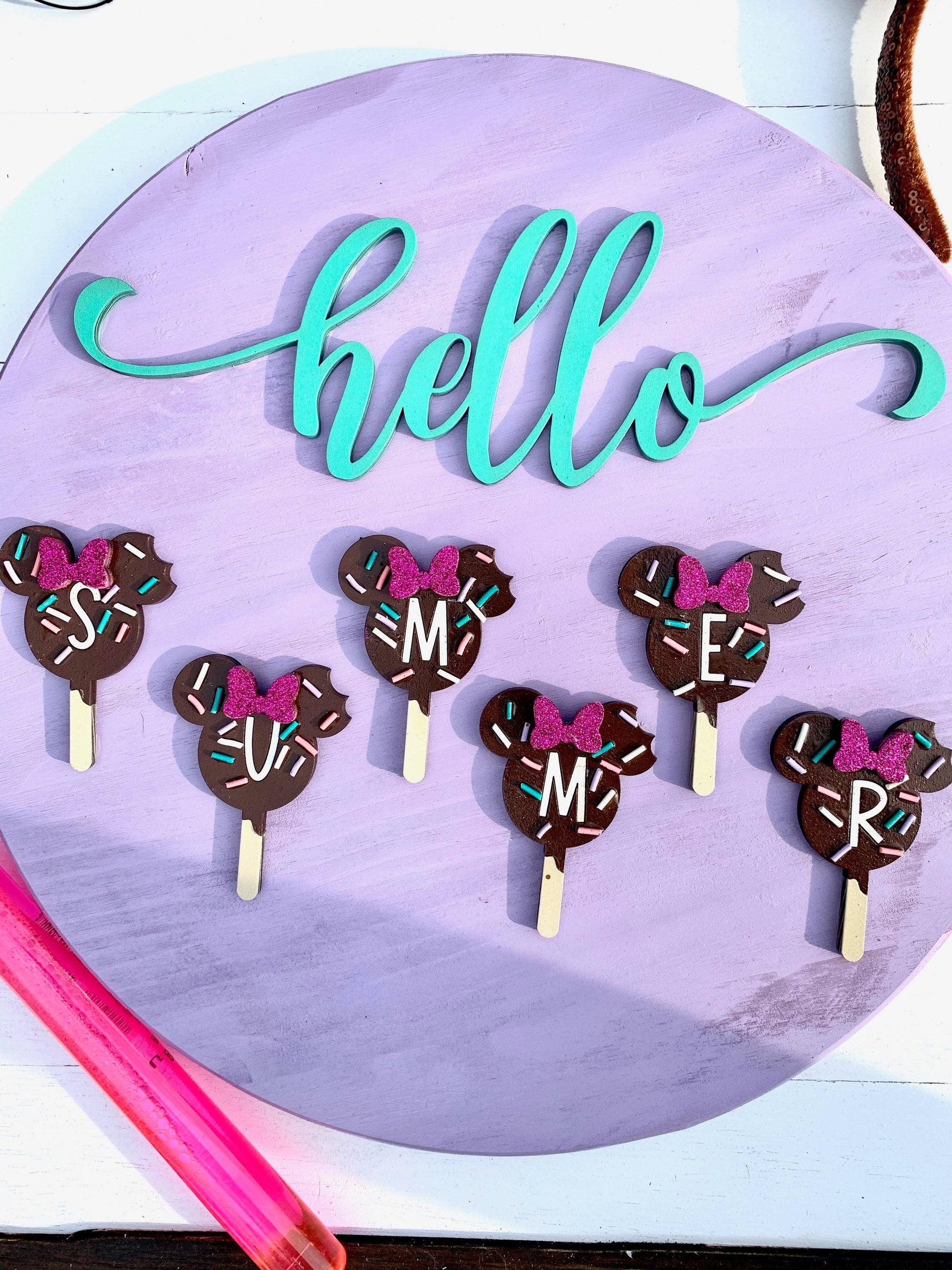Chocolate cake pops with decorative bows and letters on a purple background with 'hello' text.