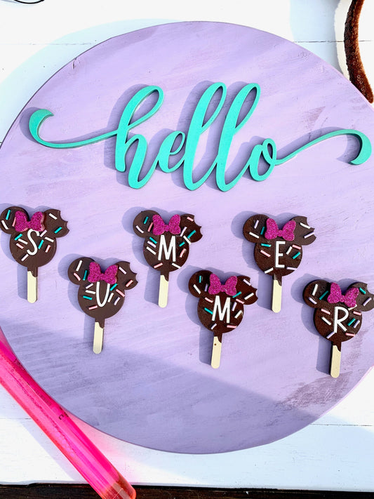Chocolate cake pops with decorative bows and letters on a purple background with 'hello' text.