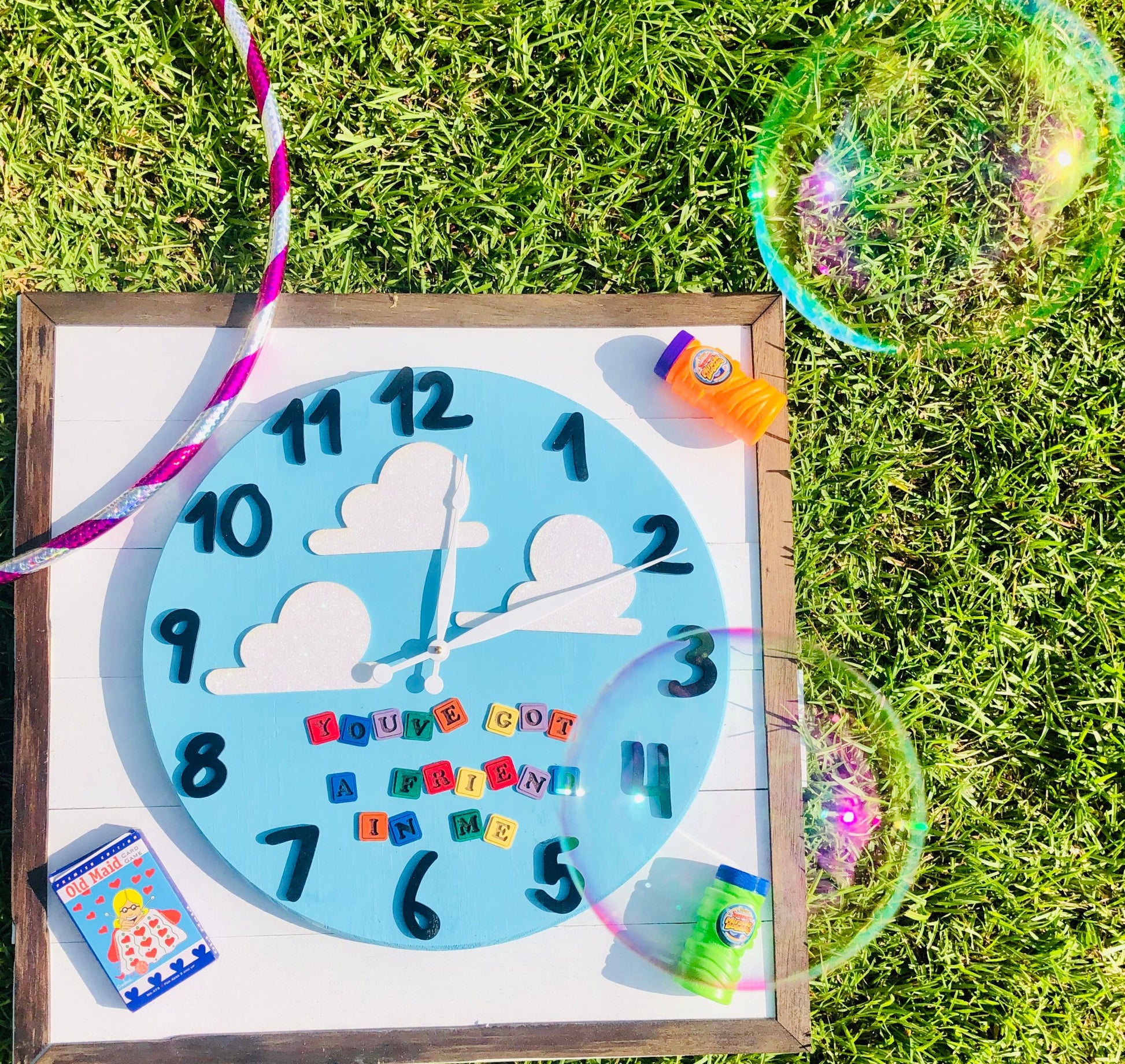 Children's clock with colorful numbers and letters on a grassy background