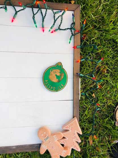Decorative sign with a green logo and gingerbread cookies on grass with Christmas lights.