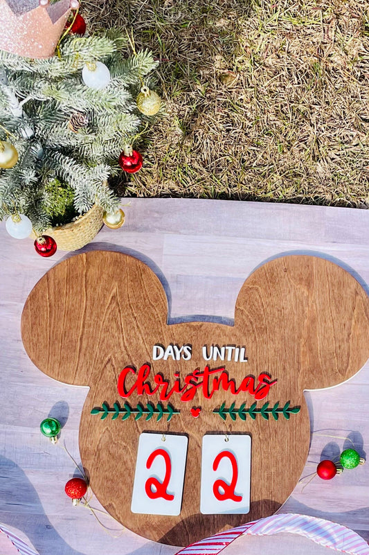 Wooden Christmas countdown calendar with Mickey Mouse design next to a decorated Christmas tree.