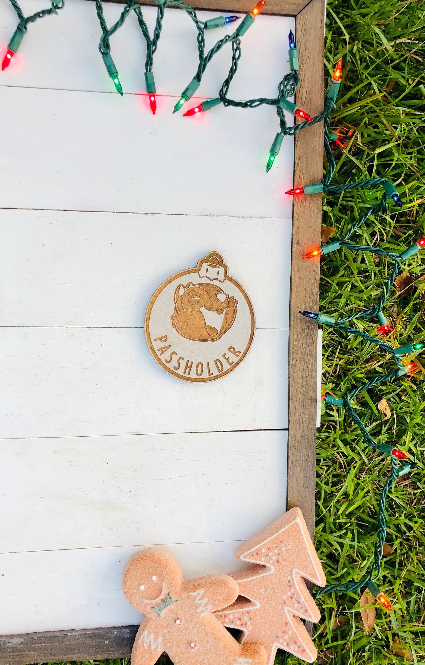 Wooden ornament with 'Passholder' branding on a white wooden board with Christmas lights.