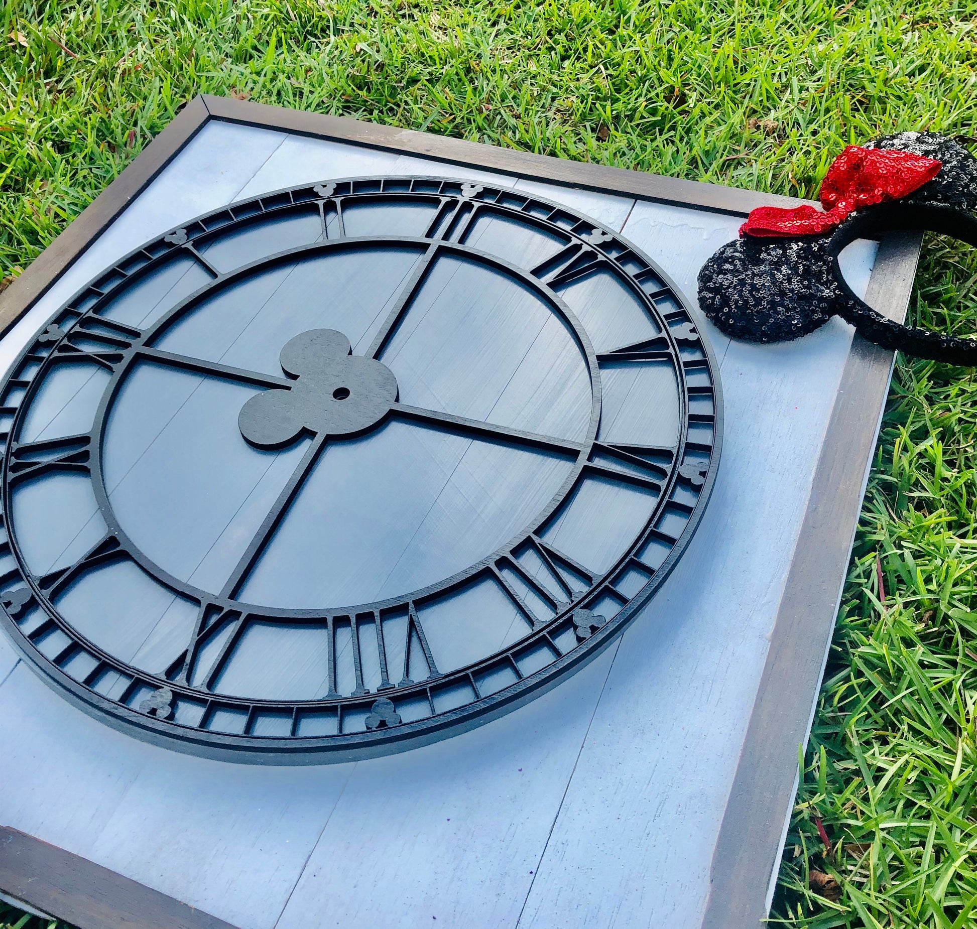 Large clock face on a stand outdoors with grass in the background
