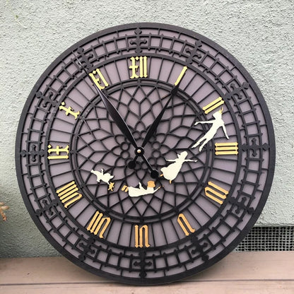 Decorative wall clock with black frame, gold Roman numerals, and white figures on a light gray wall.